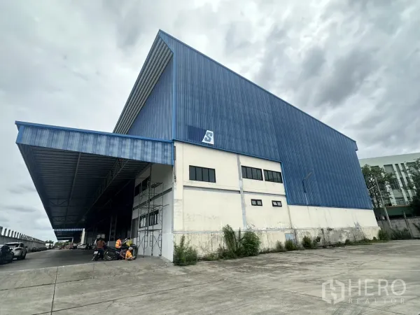 Warehouse for rent in Lat Krabang, Bangkok - Large blue-clad warehouse exterior with wide loading canopy and paved truck yard in Lat Krabang.