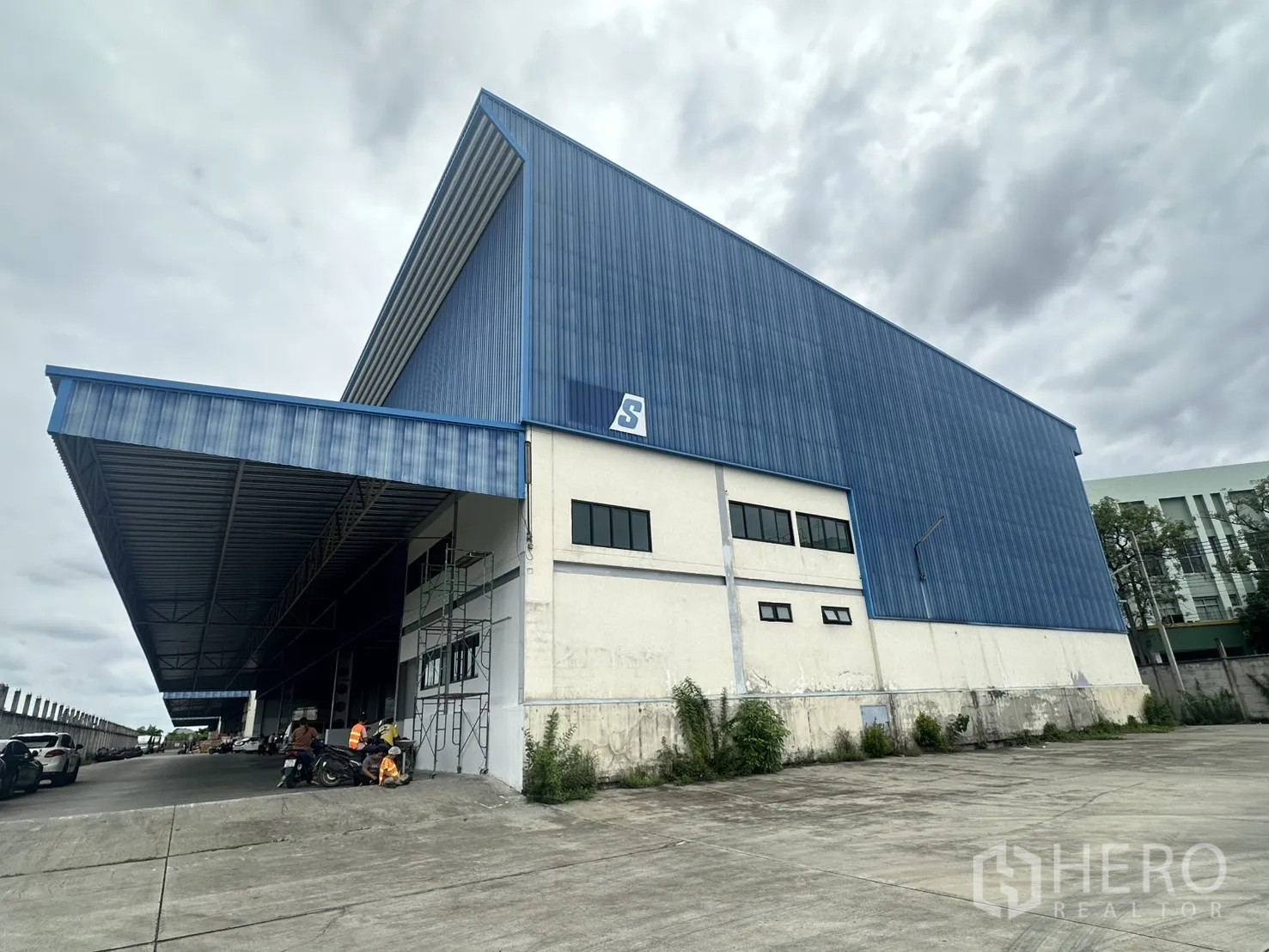 Warehouse for rent in Lat Krabang, Bangkok - Large blue-clad warehouse exterior with wide loading canopy and paved truck yard in Lat Krabang.