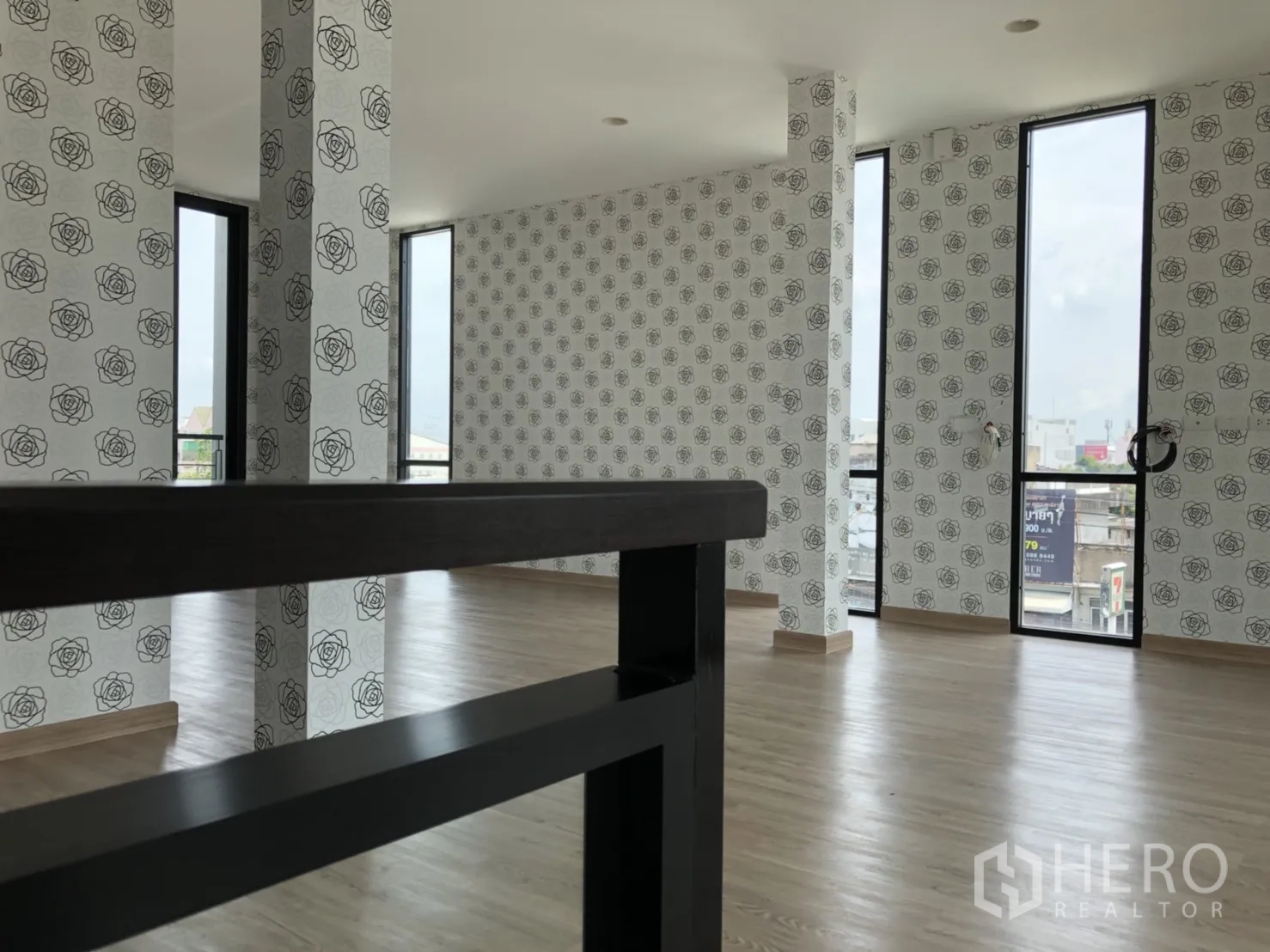 Townhouse for rent in Din Daeng, Bangkok - Upper-floor room with rose-pattern wallpaper, tall narrow windows, and wood flooring.