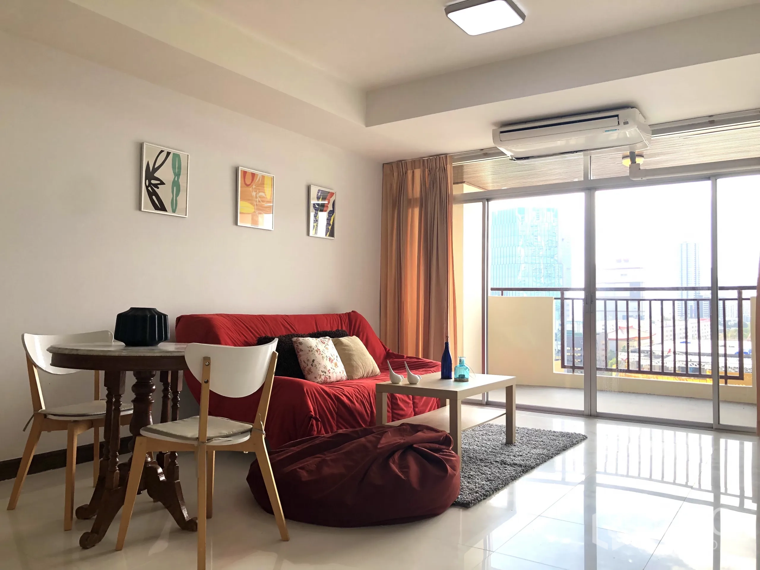 คอนโด ให้เช่าหรือขายในKhlong Toei, Bangkok - มุมนั่งเล่นหันออกไประเบียง โต๊ะกลางและพรม เห็นสกายไลน์ผ่านกระจกบานใหญ่