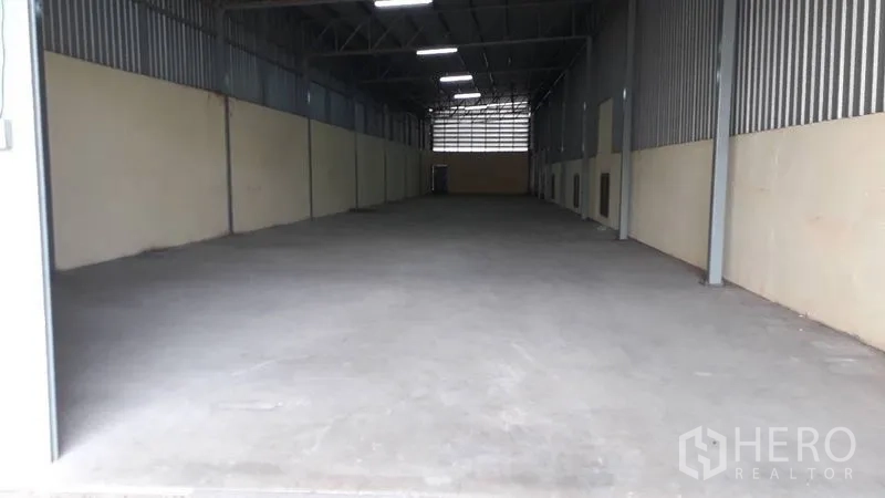 Warehouse for rent in Mueang Nakhon Pathom, Nakhon Pathom - Long warehouse interior with high ceiling, bright lighting, and smooth concrete floor.