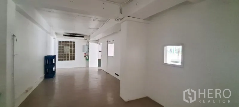 零售空间 出租在Bang Rak, Bangkok - 后勤走廊，白色墙面、玻璃砖窗、电箱与储物间。