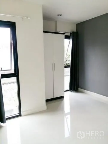 บ้าน ให้เช่าในChok Chai, Nakhon Ratchasima - มุมห้องนอนสว่าง ตู้เสื้อผ้าสีขาว ผนังสีเทา และหน้าต่างสูงมีผ้าม่าน