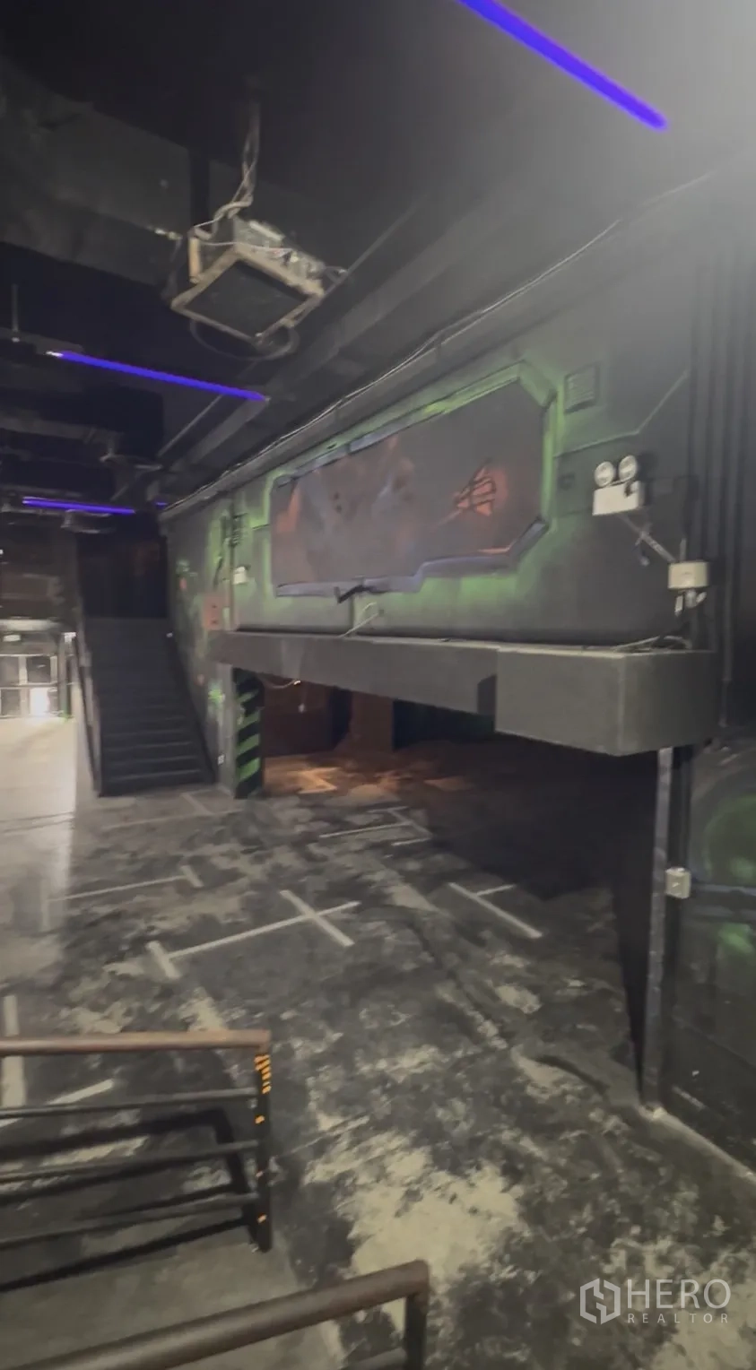 零售空间 出租在Khlong Toei, Bangkok - 夹层与楼梯近景，墙面科幻风壁画与紫色灯光。