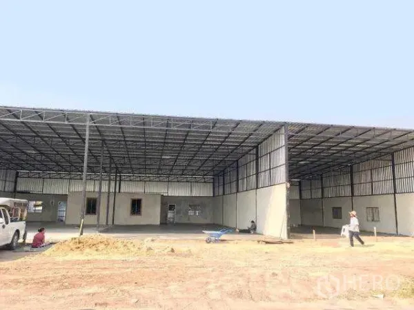 Warehouse for rent in Pathum Thani - Large steel-frame warehouse with a high roof and open concrete forecourt under construction.