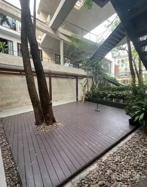 พื้นที่ขายปลีก ให้เช่าในWatthana, Bangkok - คอร์ตยาร์ดเปิดโล่งพื้นไม้ มีต้นไม้ใหญ่และทางเดินคอนกรีต