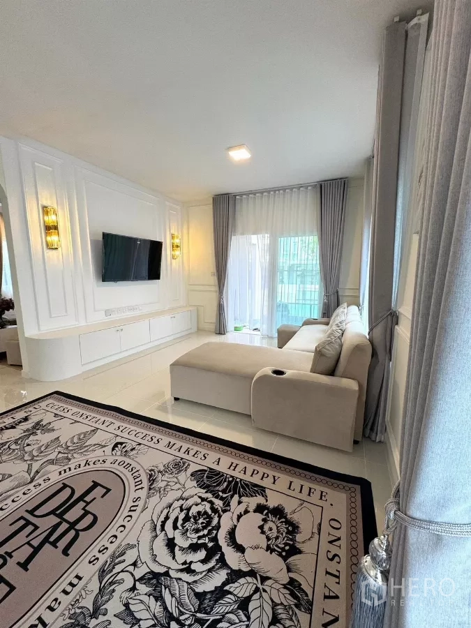 Detached House for rent in Bang Phli, Samut Prakan - TV feature wall with built-in cabinetry beside a corner sofa and tall drapes.
