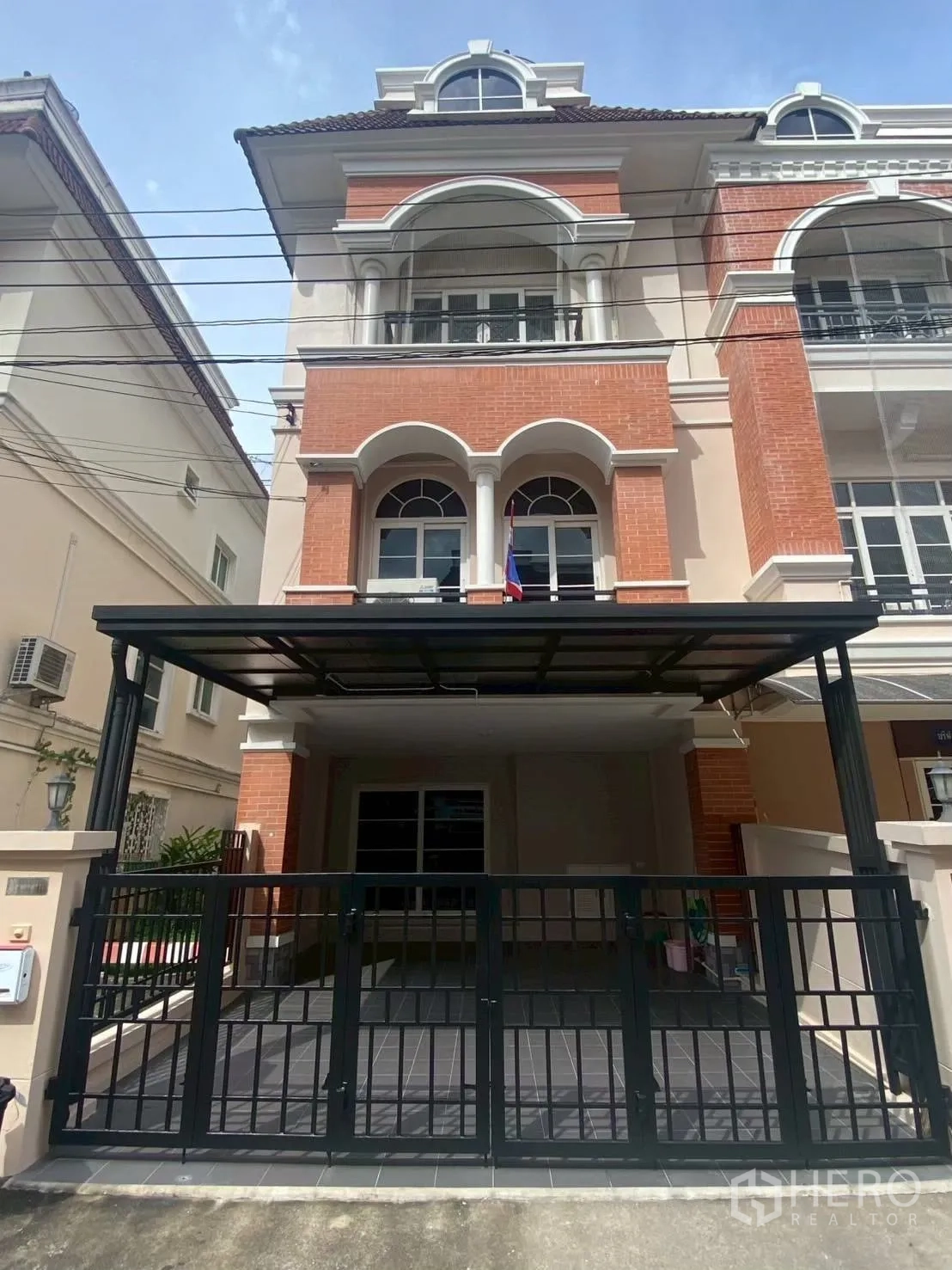 Townhouse for rent in Bang Kapi, Bangkok - Three-story brick facade with arched windows and balconies.