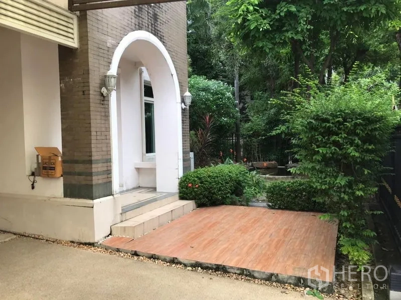 独立式住宅 出租在Bang Khen, Bangkok - 入户区拱形门廊、露台与修剪整齐的绿化。