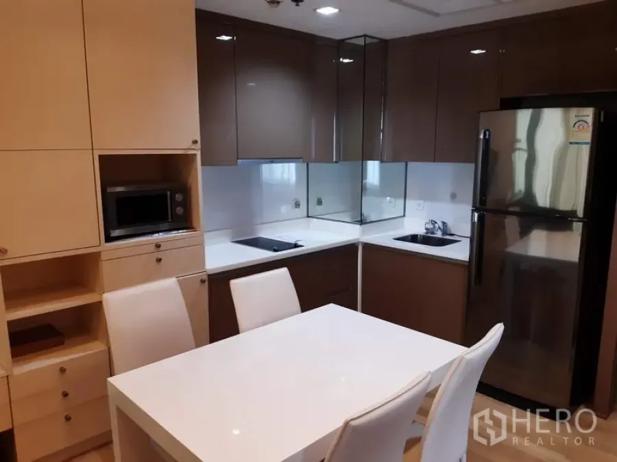 คอนโด ให้เช่าในKhlong Toei, Bangkok - ครัวบิวท์อินสไตล์โมเดิร์น ตู้ลิ้นชักเงา เตาไฟฟ้า ไมโครเวฟ ตู้เย็น และโต๊ะรับประทานอาหาร 4 ที่นั่ง