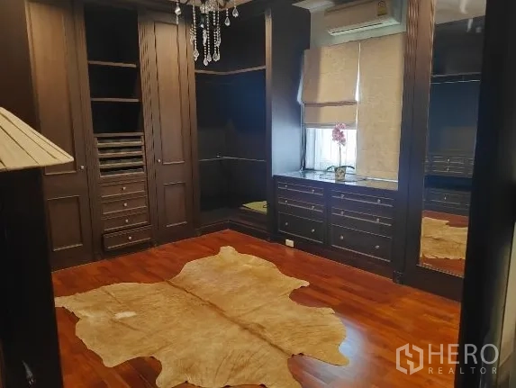 Detached House for rent in Huai Khwang, Bangkok - Walk-in closet with dark wood cabinetry and chandelier