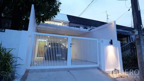 Townhouse for rent in Khlong Toei, Bangkok - Modern white townhouse facade with gated covered carport at dusk