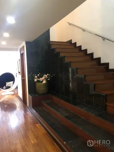 คอนโด ขาย - บันไดภายในบ้านขั้นไม้ ผนังหินสีเข้ม เชื่อมสู่โถงทางเดินที่มีไฟดาวน์ไลท์
