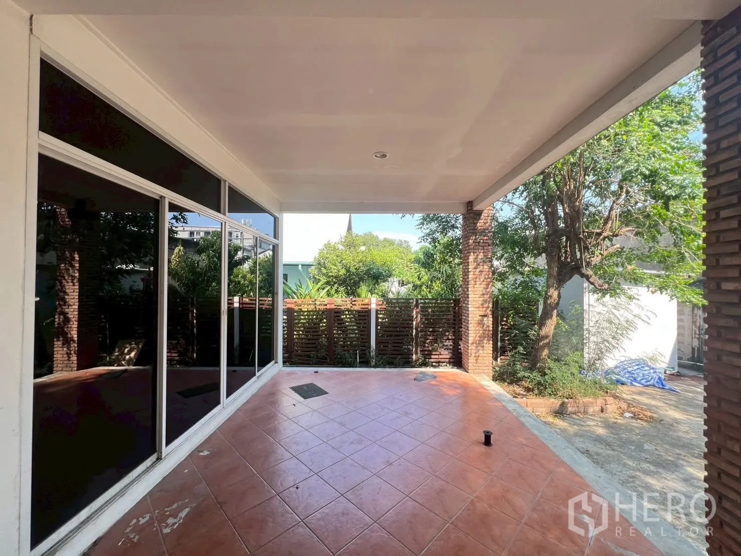 Detached House for rent in Watthana, Bangkok - Covered outdoor terrace with tiled floor overlooking a leafy yard.