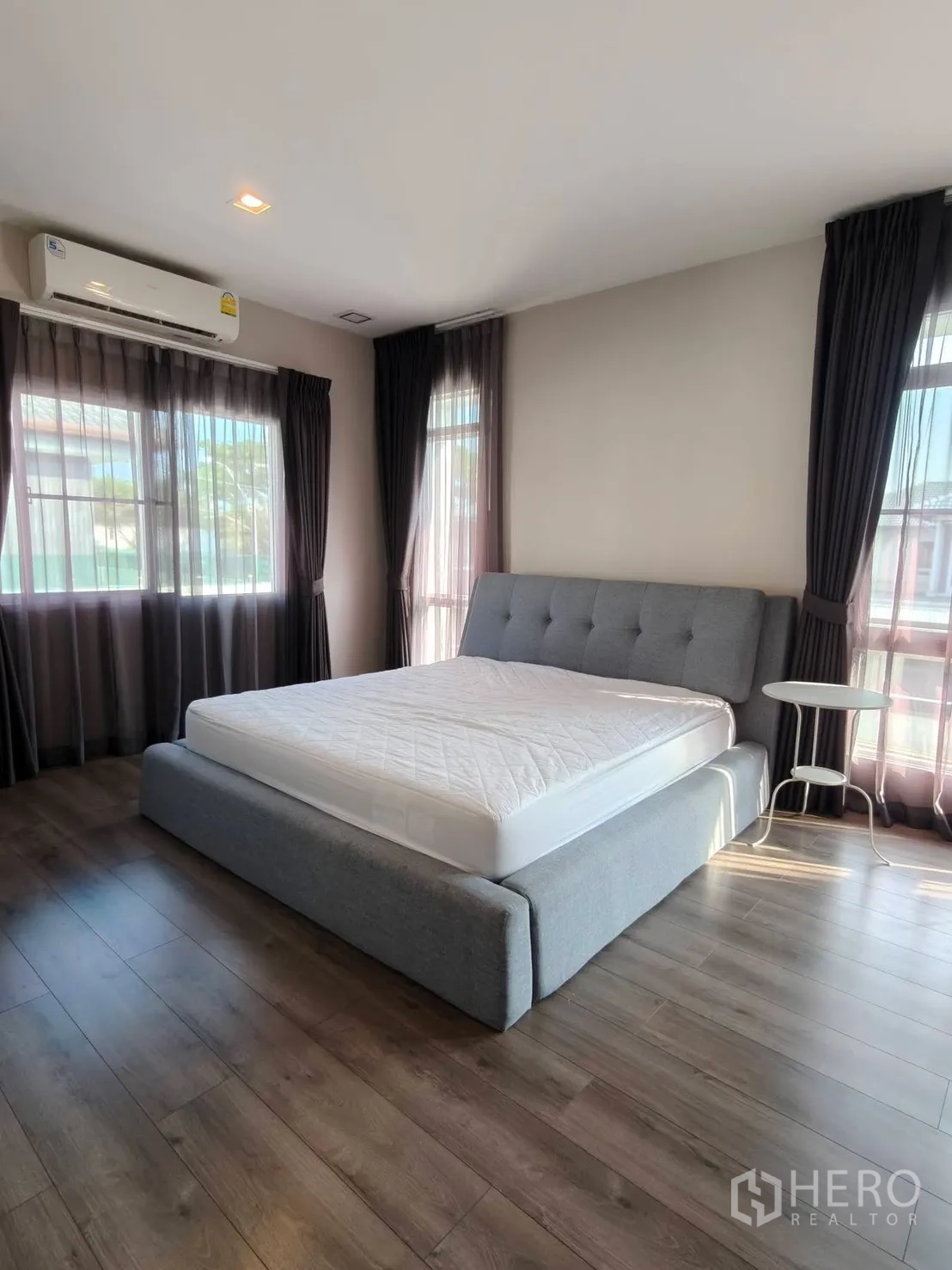 独栋房屋 for rent or sale in Bang Phli, Samut Prakan - 转角卧室，配大窗、深色窗帘与木地板。