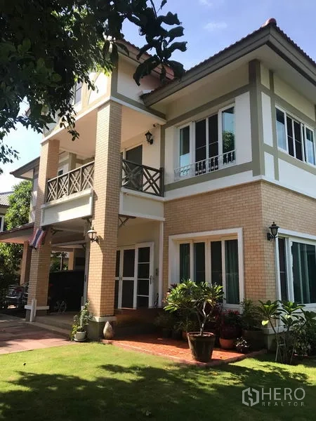 Detached House for sale in Pak Kret, Nonthaburi - Two-storey detached house exterior in Pak Kret with brick facade, balcony and manicured lawn.