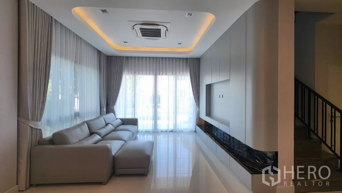 บ้าน ให้เช่าหรือขายในBueng Kum, Bangkok - ห้องนั่งเล่นสว่าง โซฟารูปตัวแอล บิลต์อินทีวี แอร์ฝังฝ้าแบบคาสเซ็ต ผ้าม่านสูงจรดเพดาน