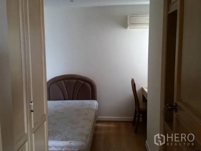 Condominium for rent in Watthana, Bangkok - Cozy second bedroom with bed, wardrobe, and study desk beneath an air conditioner.