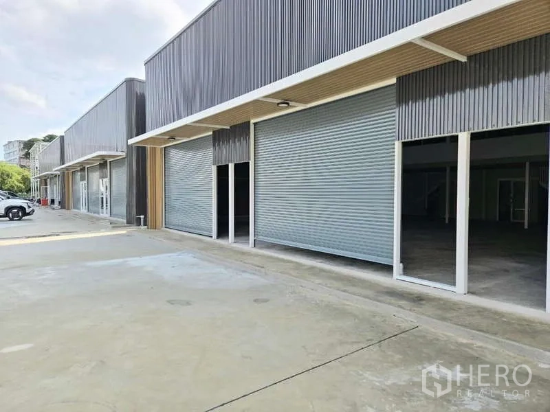 Warehouse for rent in Wang Thonglang, Bangkok - Row of modern warehouse units in Wang Thonglang with roller shutter doors and a wide driveway.