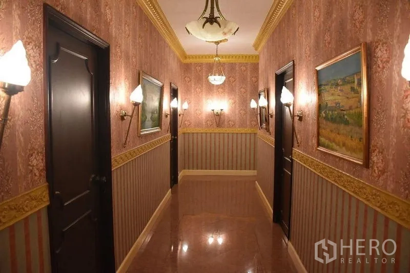 คอนโด ให้เช่าในWatthana, Bangkok - โถงทางเดินยาวติดไฟกิ่ง ภาพวาด และประตูไม้สีเข้มไปยังห้องนอน