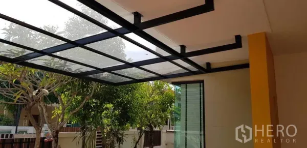 Detached House for rent in Bang Phli, Samut Prakan - Covered patio featuring a steel-and-glass canopy beside sliding doors and a leafy garden.