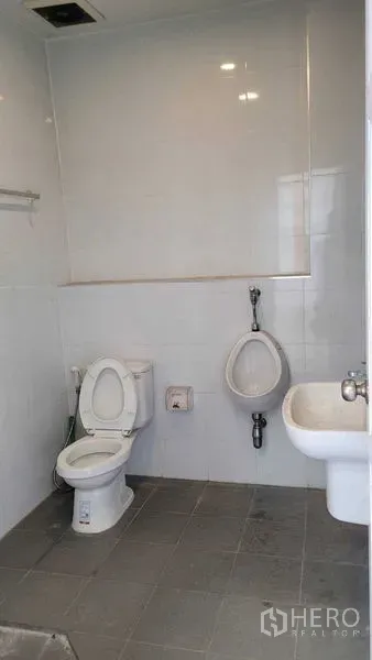 Warehouse for rent in Saphan Sung, Bangkok - Clean tiled restroom with toilet, urinal, and sink inside the facility.