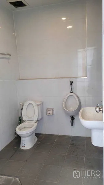 Warehouse for rent in Saphan Sung, Bangkok - Clean tiled restroom with toilet, urinal, and sink inside the facility.