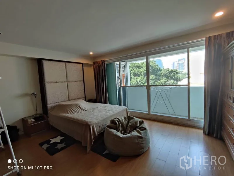 คอนโด ให้เช่าในWatthana, Bangkok - ห้องนอนมีหน้าต่างเต็มผนังและระเบียง มองเห็นต้นไม้และวิวเมือง