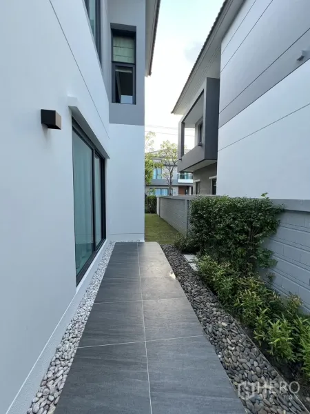 Detached House for rent or sale in Bang Phli, Samut Prakan - Side walkway with large gray tiles, white pebble border and planting strip.