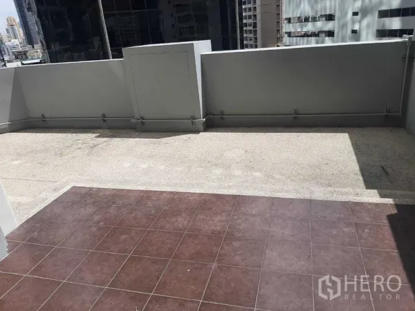 Condominium for rent or sale in Huai Khwang, Bangkok - Large outdoor terrace with tiled and gravel flooring and high privacy walls overlooking city buildings.