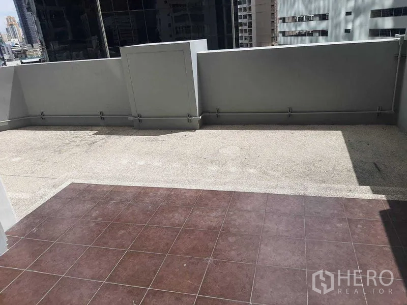 Condominium for rent or sale in Huai Khwang, Bangkok - Large outdoor terrace with tiled and gravel flooring and high privacy walls overlooking city buildings.