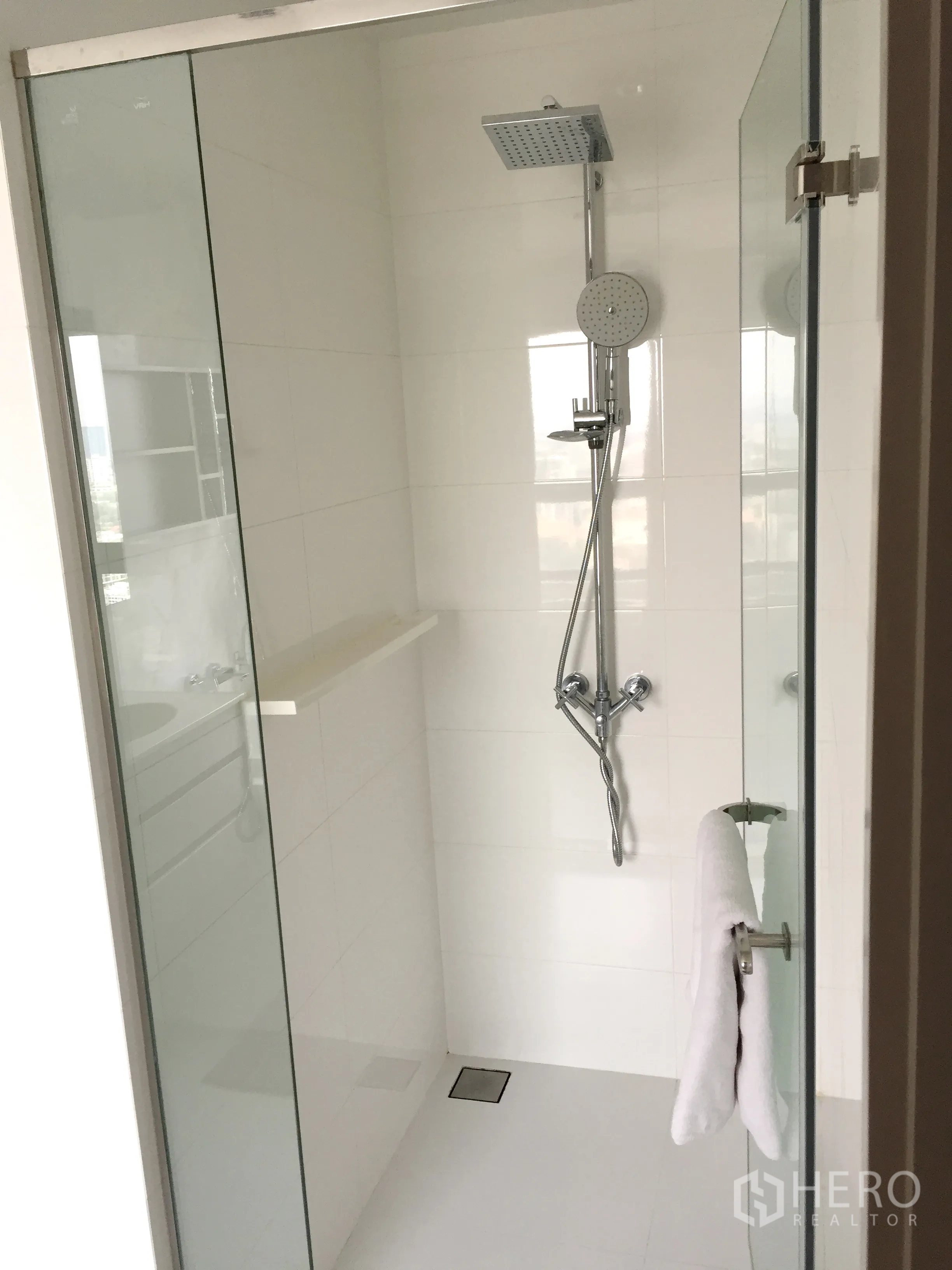 Condominium for rent in Watthana, Bangkok - Glass-enclosed shower with rainfall and handheld showerheads in a white-tiled bathroom.
