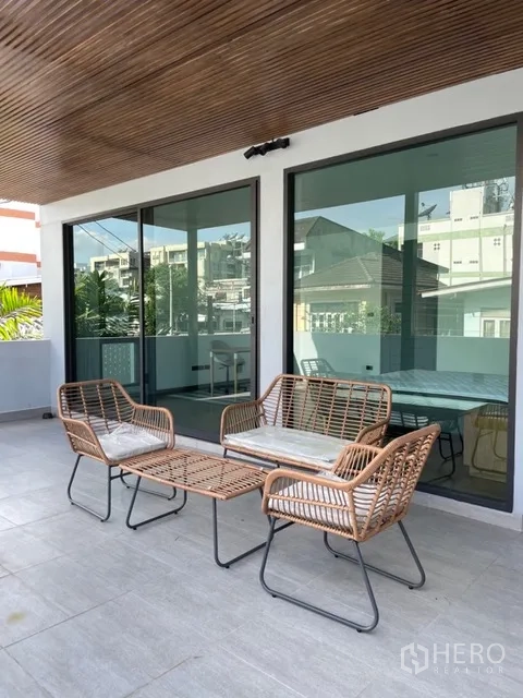 Detached House for rent in Watthana, Bangkok - Covered terrace with rattan outdoor seating and large sliding doors.