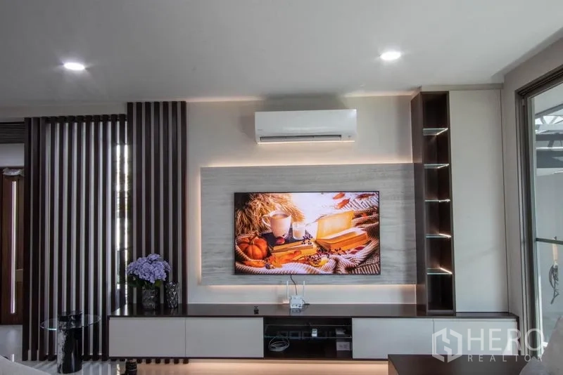 Detached House for sale in Saphan Sung, Bangkok - Built-in TV wall with LED accent lighting, shelving and air conditioner in a modern living room.