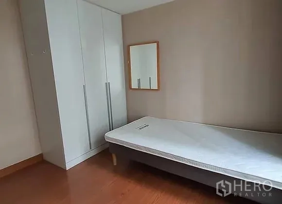 Condominium for rent in Huai Khwang, Bangkok - Third bedroom with single bed, white wardrobe and wall mirror.