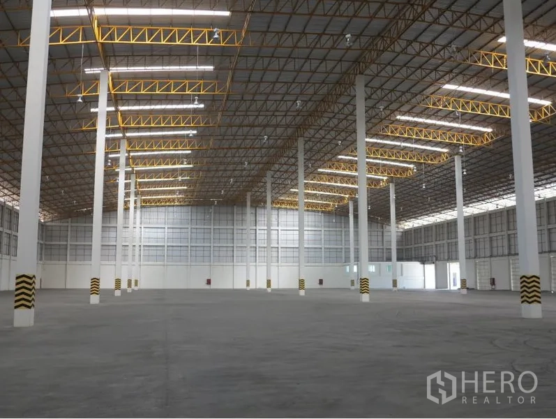 货栈 出租在Lopburi - 高挑层高的仓库内部，白色立柱与黄色桁架