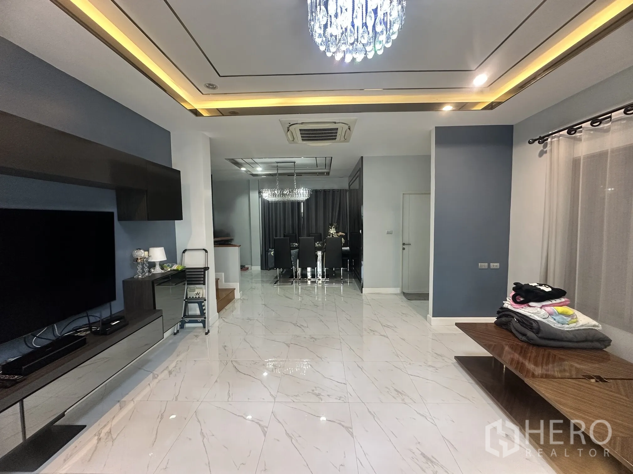 Detached House for sale in Pak Kret, Nonthaburi - Open-plan living and dining area with marble-look floors and a chandelier.