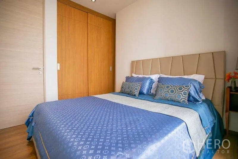 คอนโด ขายในKhlong Toei, Bangkok - มุมห้องนอนเห็นตู้เสื้อผ้าบิวท์อินไม้และหัวเตียงบุผ้า