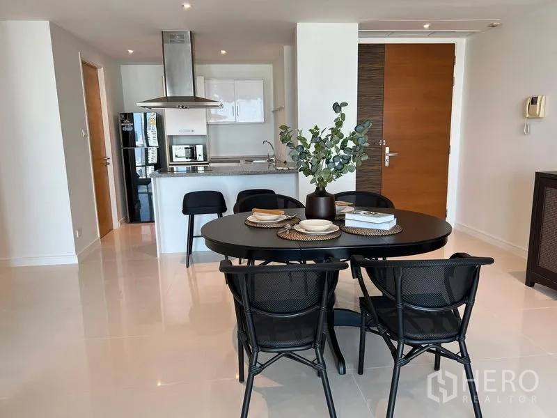 Condominium for rent in Watthana, Bangkok - Dining area facing a modern open kitchen with breakfast bar, stainless hood and full-size appliances.