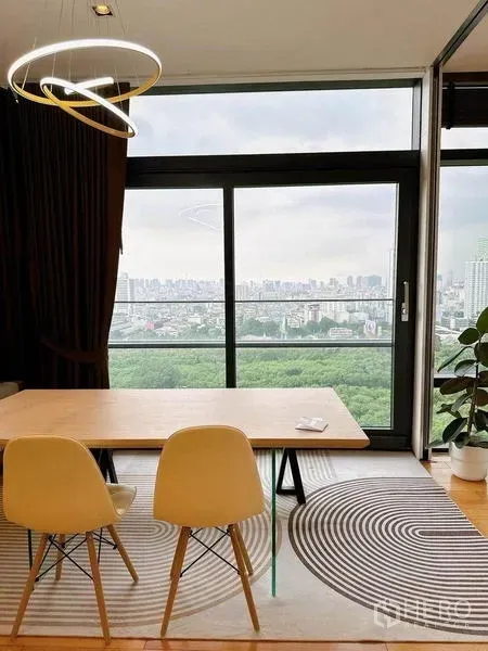 Condominium for rent in Ratchathewi, Bangkok - Dining nook with two chairs on a patterned rug beside a sliding glass door and expansive city view.