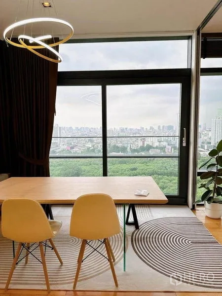 Condominium for rent in Ratchathewi, Bangkok - Dining nook with two chairs on a patterned rug beside a sliding glass door and expansive city view.