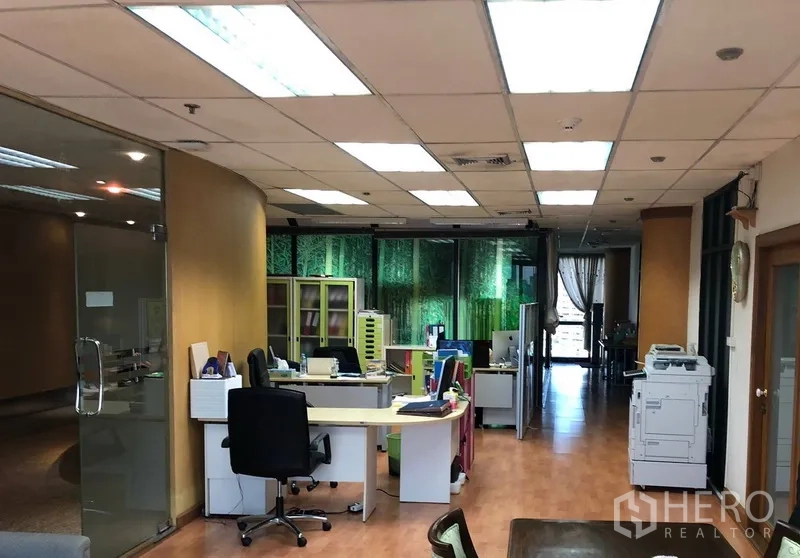 Office Space for rent in Bang Na, Bangkok - Open-plan workspace with desks, glass partitions, wood flooring and ceiling lights.