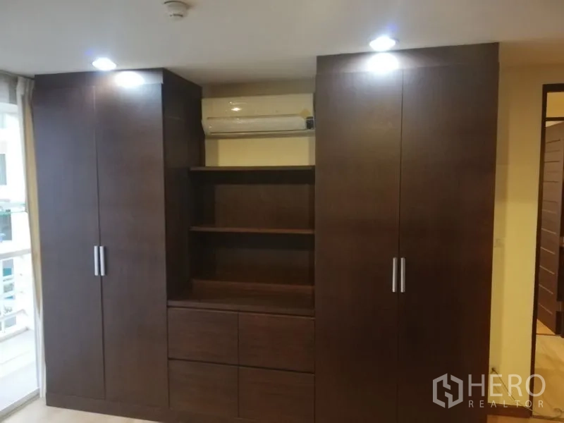 Condominium for rent in Watthana, Bangkok - Built-in dark wood wardrobes with shelving and overhead air conditioning unit.