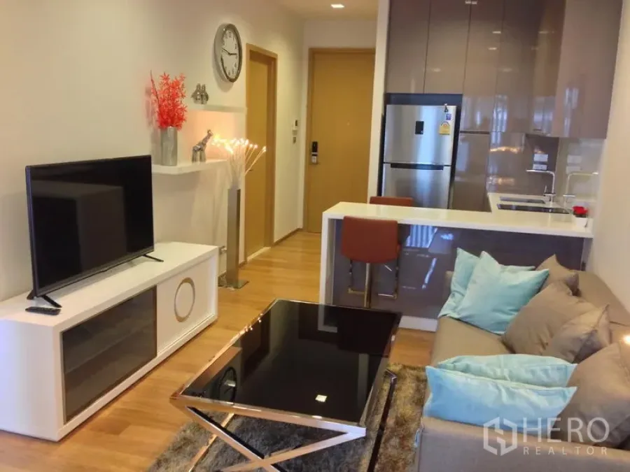 คอนโด ให้เช่าในWatthana, Bangkok - ห้องนั่งเล่นแบบโอเพนแพลน พร้อมโซฟา ชั้นวางทีวี ครัวบิวต์อินและเคาน์เตอร์ทานอาหารในคอนโดกรุงเทพฯ