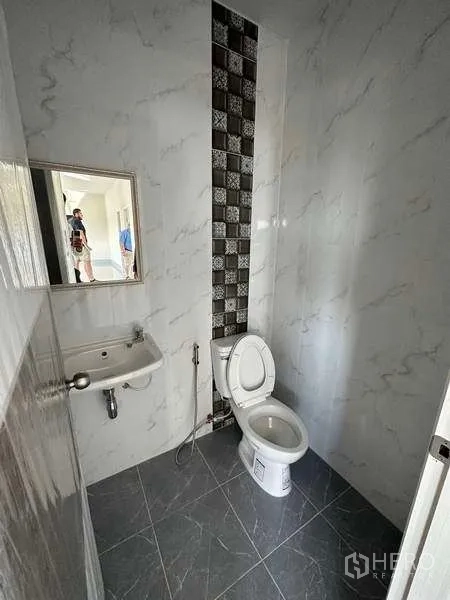 工厂 出租或出售在Sai Noi, Nonthaburi - 办公室内的瓷砖卫生间，配马桶与壁挂洗手盆。