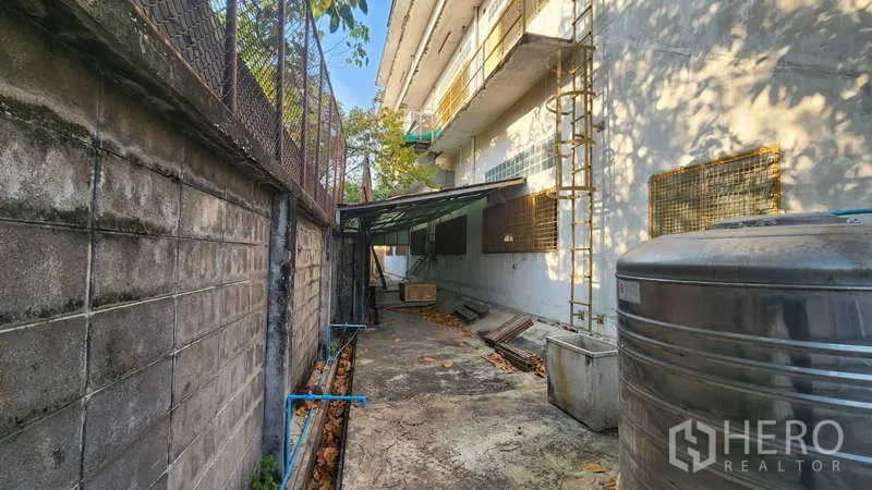 工厂 出租在Chom Thong, Bangkok - 建筑侧服务通道，水塔、管线与围墙。