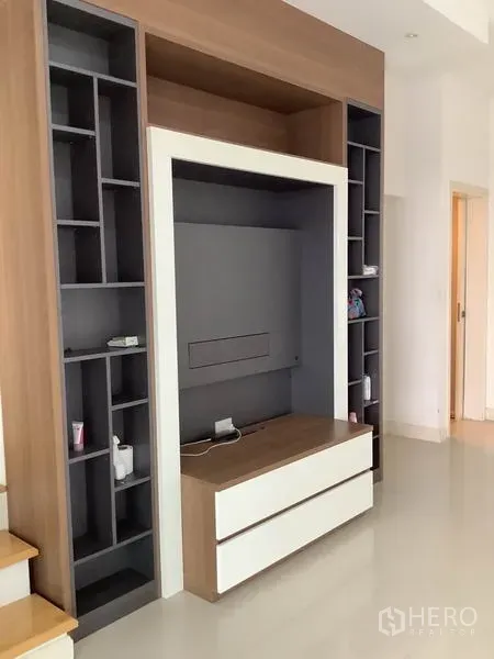 联排别墅 出租或出售在Wang Thonglang, Bangkok - 客厅内的木色与灰色组合电视墙，带开放格架和抽屉柜。