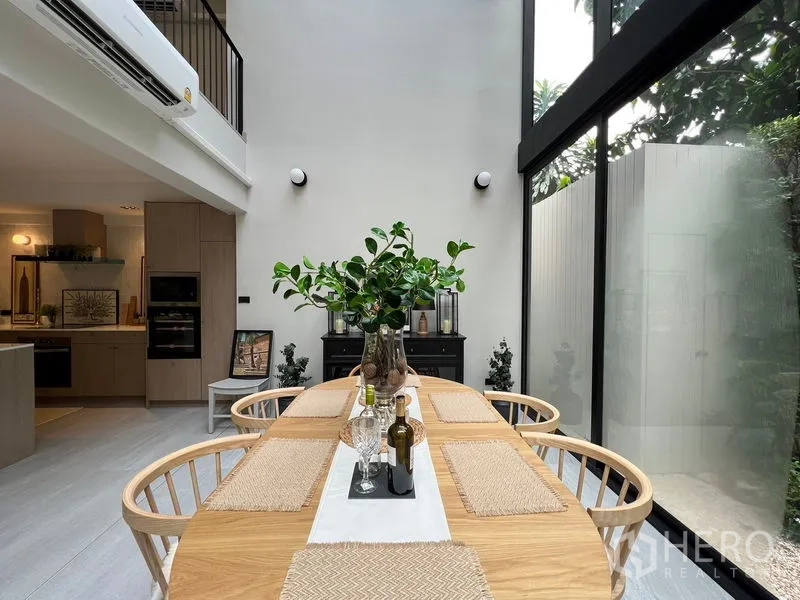 联排别墅 出售在Khlong Toei, Bangkok - 花园中庭下的餐桌，双层挑高玻璃引入绿意。