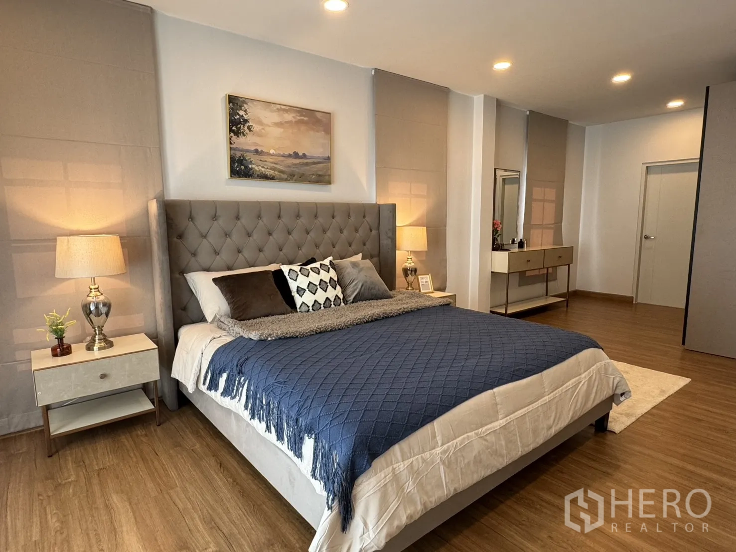 Detached House for rent in Bang Phli, Samut Prakan - Master bedroom with tufted headboard, bedside lamps and wood floors in a spacious setting.