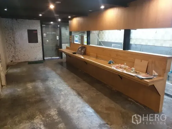 อาคารพาณิชย์ ให้เช่าในKhlong Toei, Bangkok - พื้นที่ชั้นล่างพร้อมเคาน์เตอร์ไม้ยาว พื้นปูนขัดมัน และประตูกระจกม้วน